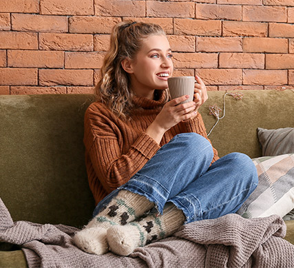 Visa Girl sitting on couch with cup in hand