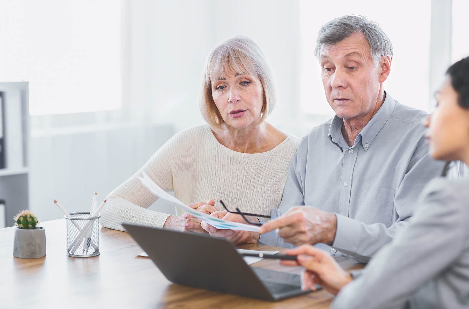 A senior couple sit at a table with an advisor to learn about personal loan interest rates