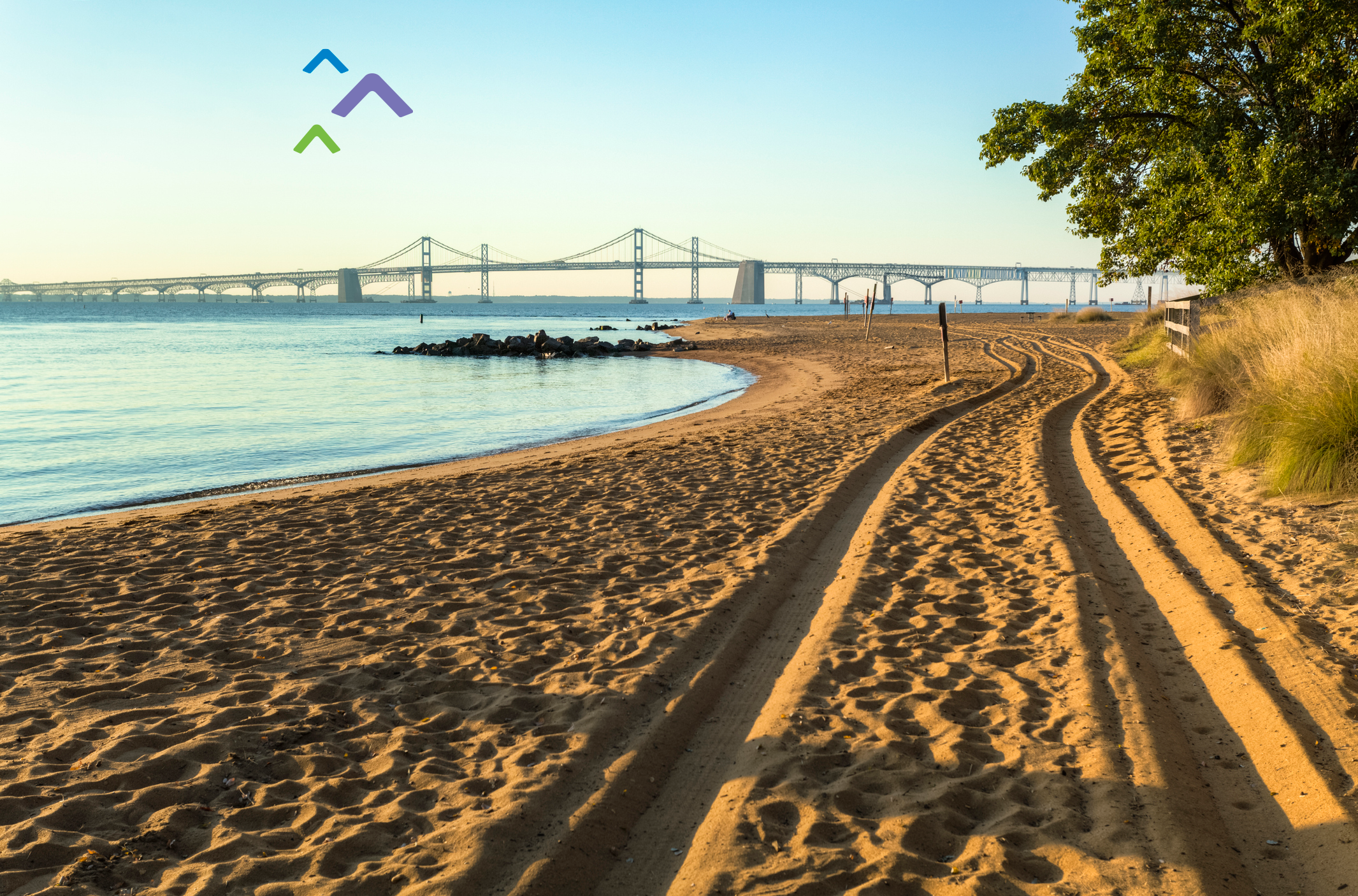 Photo of the Chesapeake Bay Bridge taken from a sandy shore.
